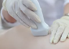 doctor-holding-ultrasound-probe-on-breast-of-female-patient-in-clinic-closeup.png